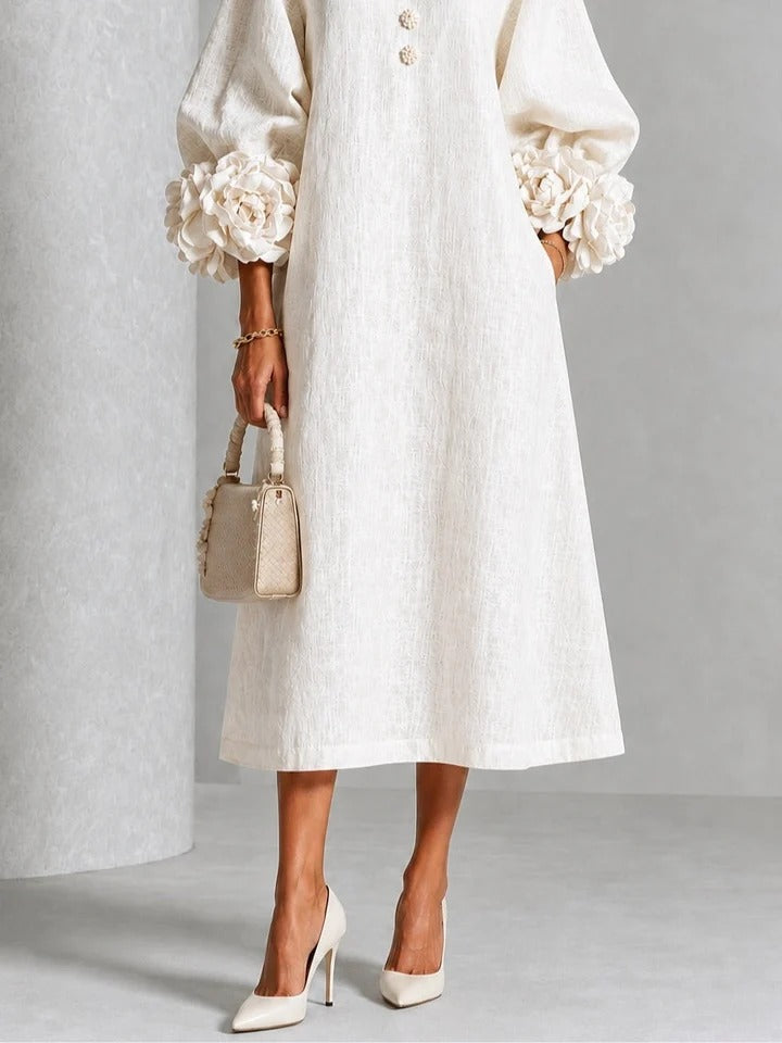 Vestido midi blanco con botones florales y mangas decoradas.